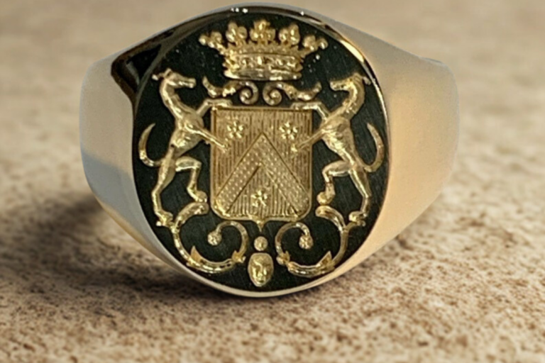 Chevalière en or gravée d’un écu surmonté d’une couronne héraldique avec supports animaux décoratifs.