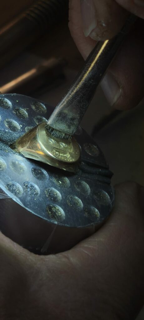 Vérifications et empreintes- Eric Leroy meilleur ouvrier de France terminant les finitions du blason gravé. Avec le pinceau enlève les restant de copeaux et de poussière d'or 