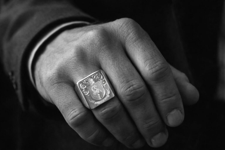 Chevalière en argent portée par un homme, ornée d’une création d’armoiries familiales gravée artisanalement